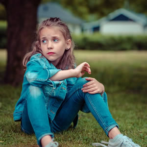 Girl Wearing Denim sitting on grass bedwetting In children
